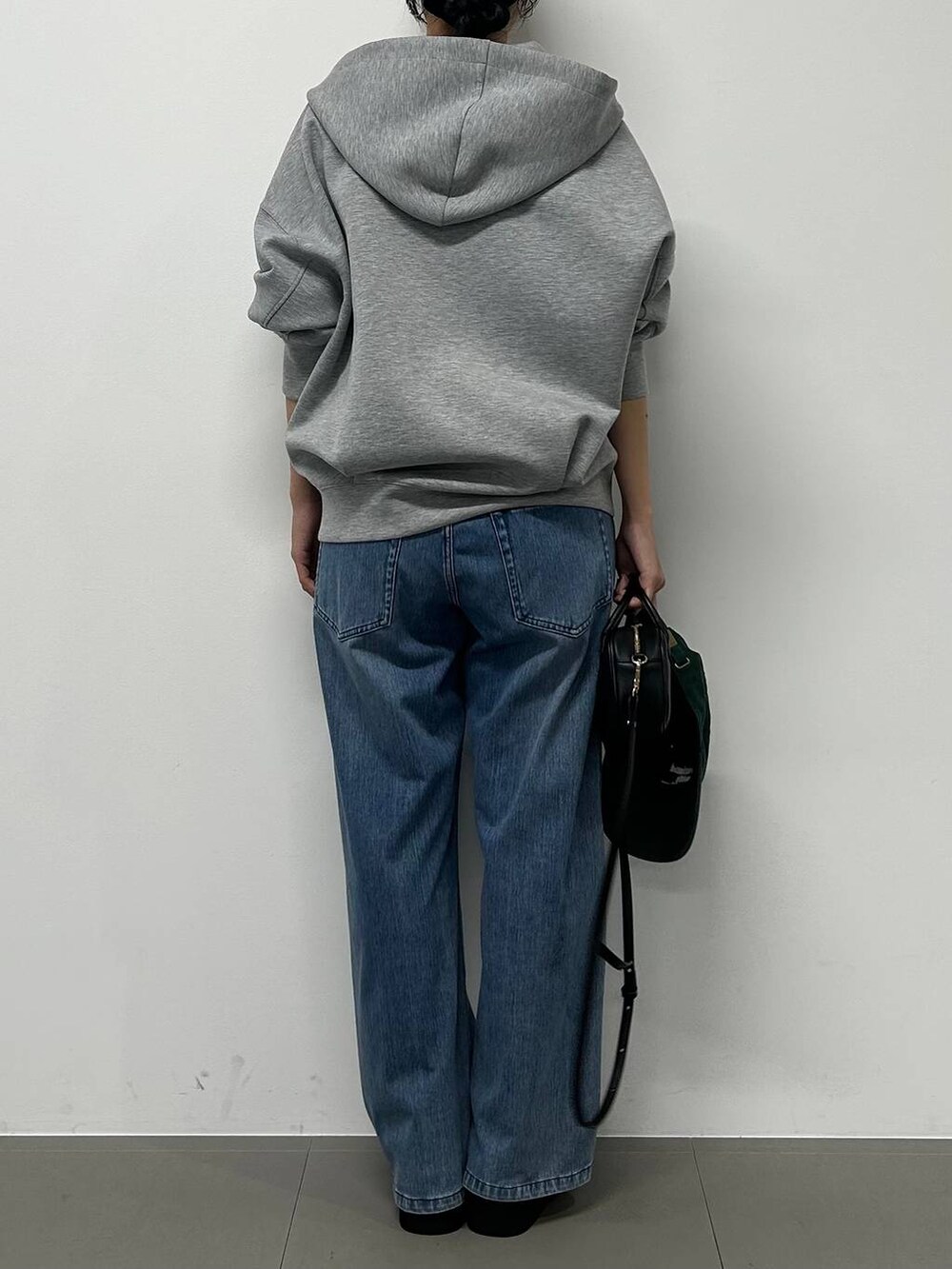 ブルー系のデニムパンツ、ブラック系のショルダーバッグ、グレー系のパーカーを着用したレディースの秋コーディネートの3枚目の写真