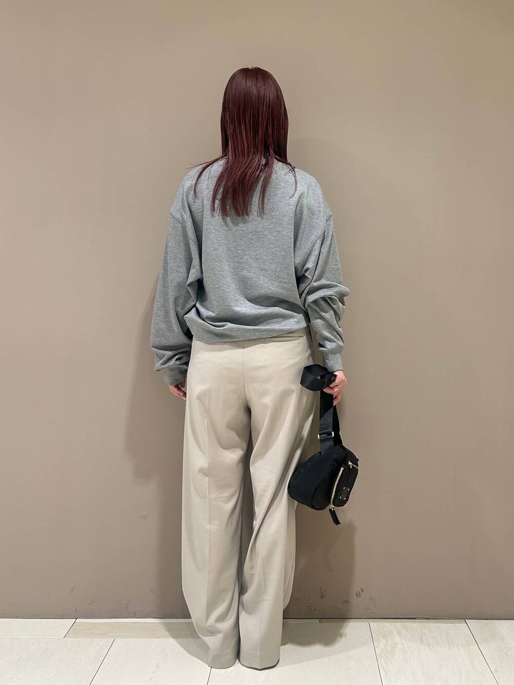 ブラック系のボディバッグ/ウエストポーチ、ホワイト系のスニーカー、ベージュ系のスラックスを着用したレディースの冬コーディネートの2枚目の写真