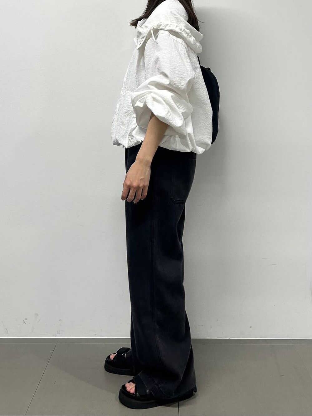 グレー系のデニムパンツ、ホワイト系のブルゾン、ブラック系のサンダルを着用したレディースの春コーディネートの2枚目の写真