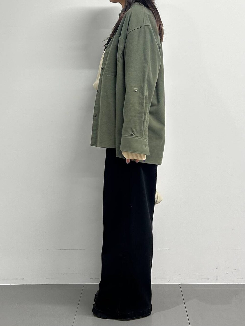 ホワイト系のショルダーバッグ、ブラック系のデニムパンツ、ブラック系のブーツを着用したレディースの秋コーディネートの2枚目の写真