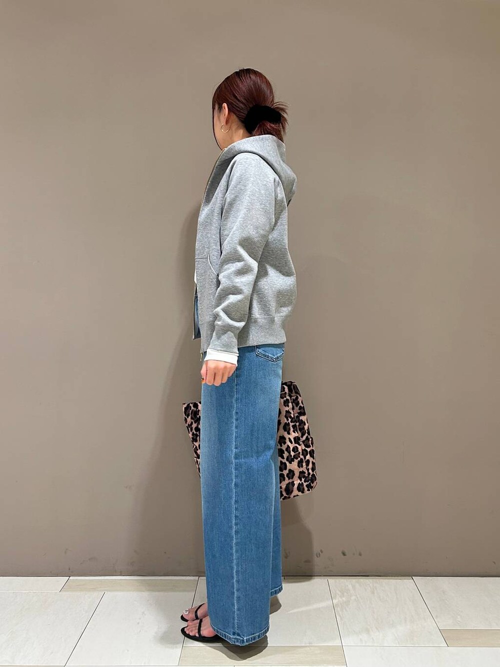 ブラック系のスリッポン、ブルー系のデニムパンツ、グレー系のパーカーを着用したレディースの春コーディネートの2枚目の写真