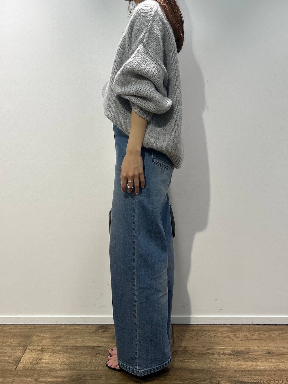 ブラック系のボストンバッグ、ブルー系のデニムパンツ、グレー系のニット/セーターを着用したレディースの秋コーディネートの2枚目の写真