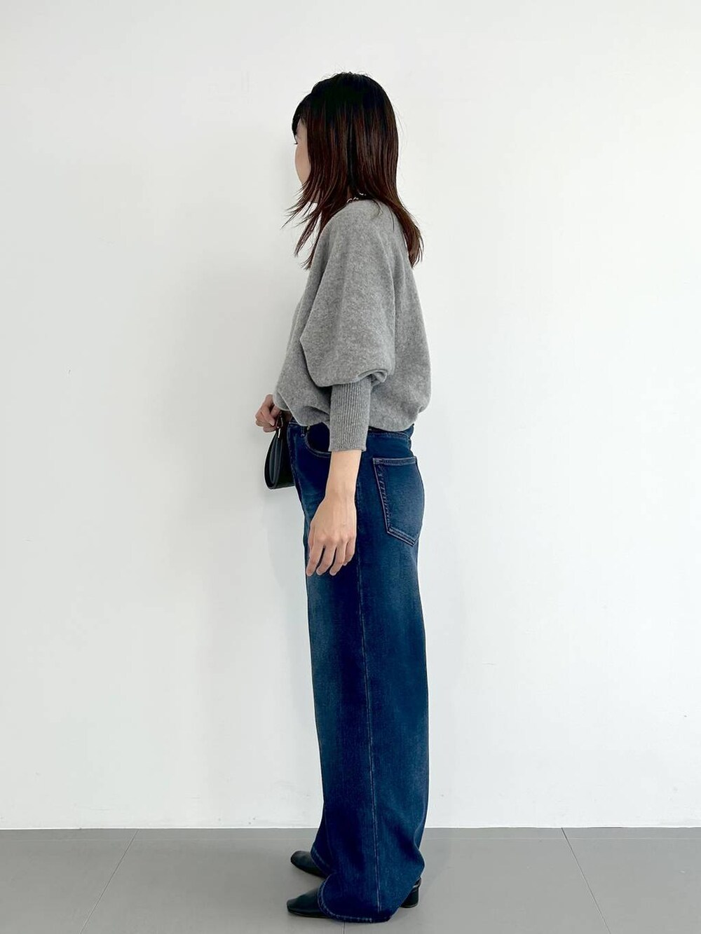 ブルー系のデニムパンツ、ブラック系のショルダーバッグ、ブラック系のパンプスを着用したレディースの秋コーディネートの2枚目の写真