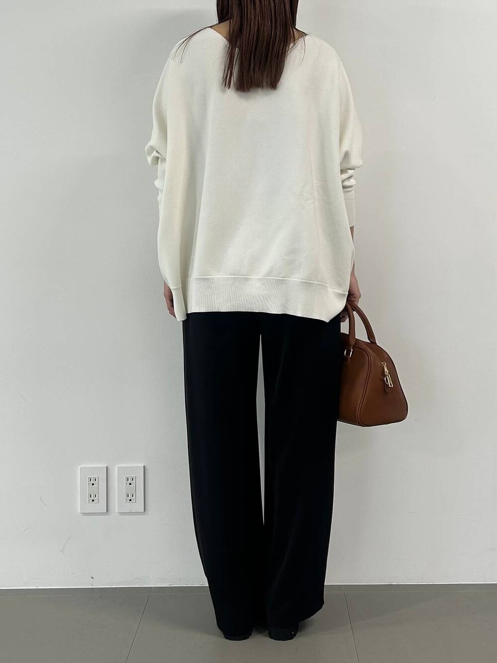 イエロー系のボストンバッグ、ブラック系のスラックス、その他のネックレスを着用したレディースの冬コーディネートの3枚目の写真