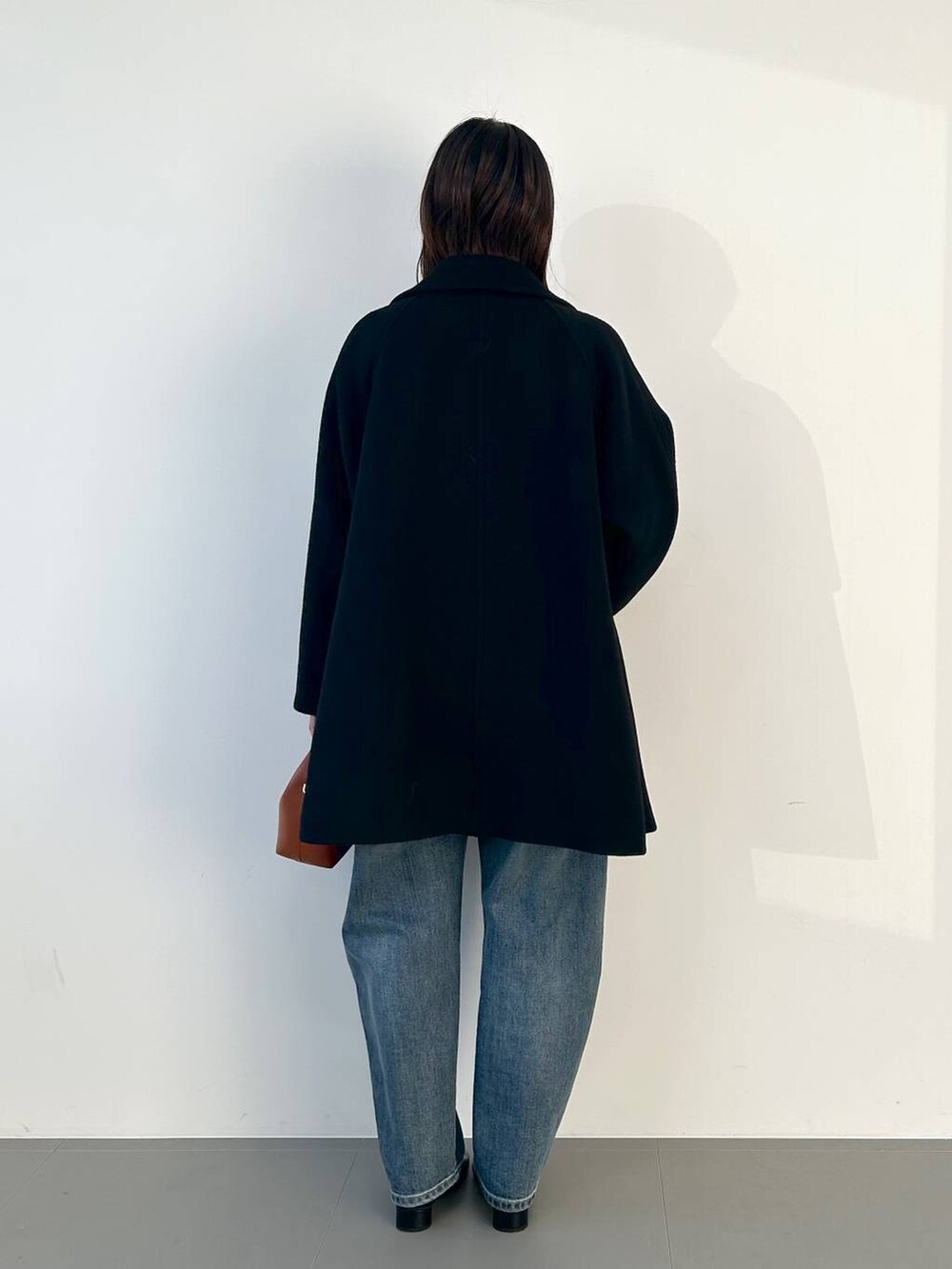 ブラウン系のショルダーバッグ、ブルー系のデニムパンツ、グレー系のニット/セーターを着用したレディースの秋コーディネートの3枚目の写真