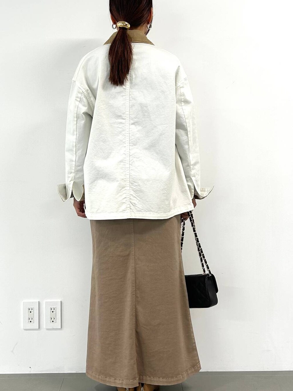 ブラウン系のスカート、ベージュ系のブーツ、ブラウン系のハンドバッグを着用したレディースの冬コーディネートの3枚目の写真