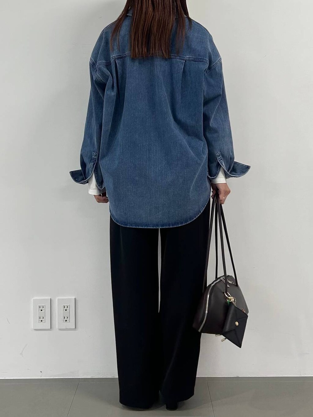 ブラウン系のトートバッグ、ブラック系のスラックスを着用したレディースの冬コーディネートの3枚目の写真