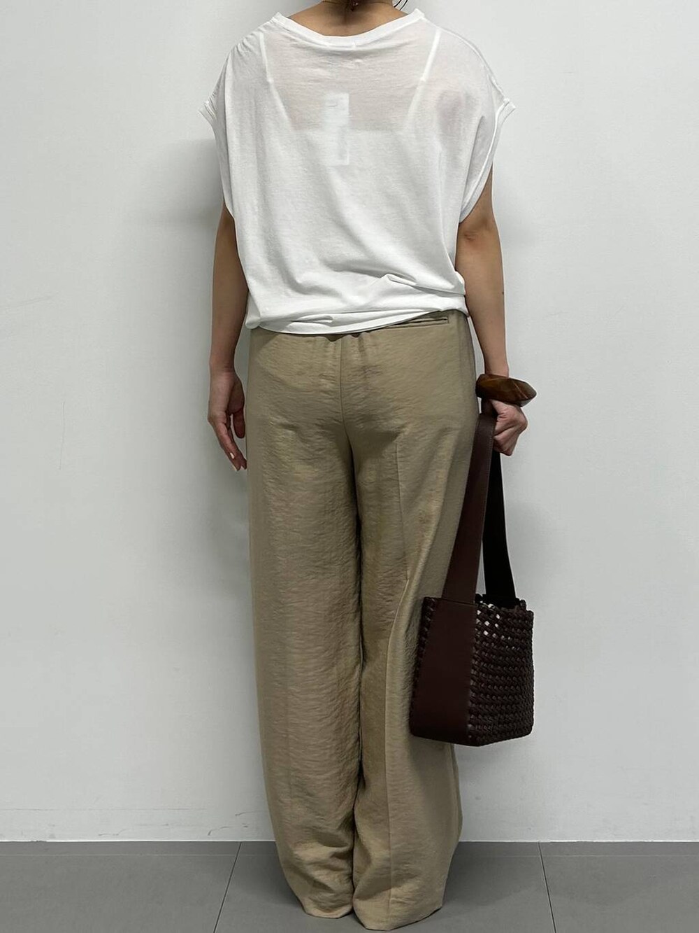 イエロー系のサンダル、ブラウン系のハンドバッグ、ベージュ系のスラックスを着用したレディースの夏コーディネートの3枚目の写真