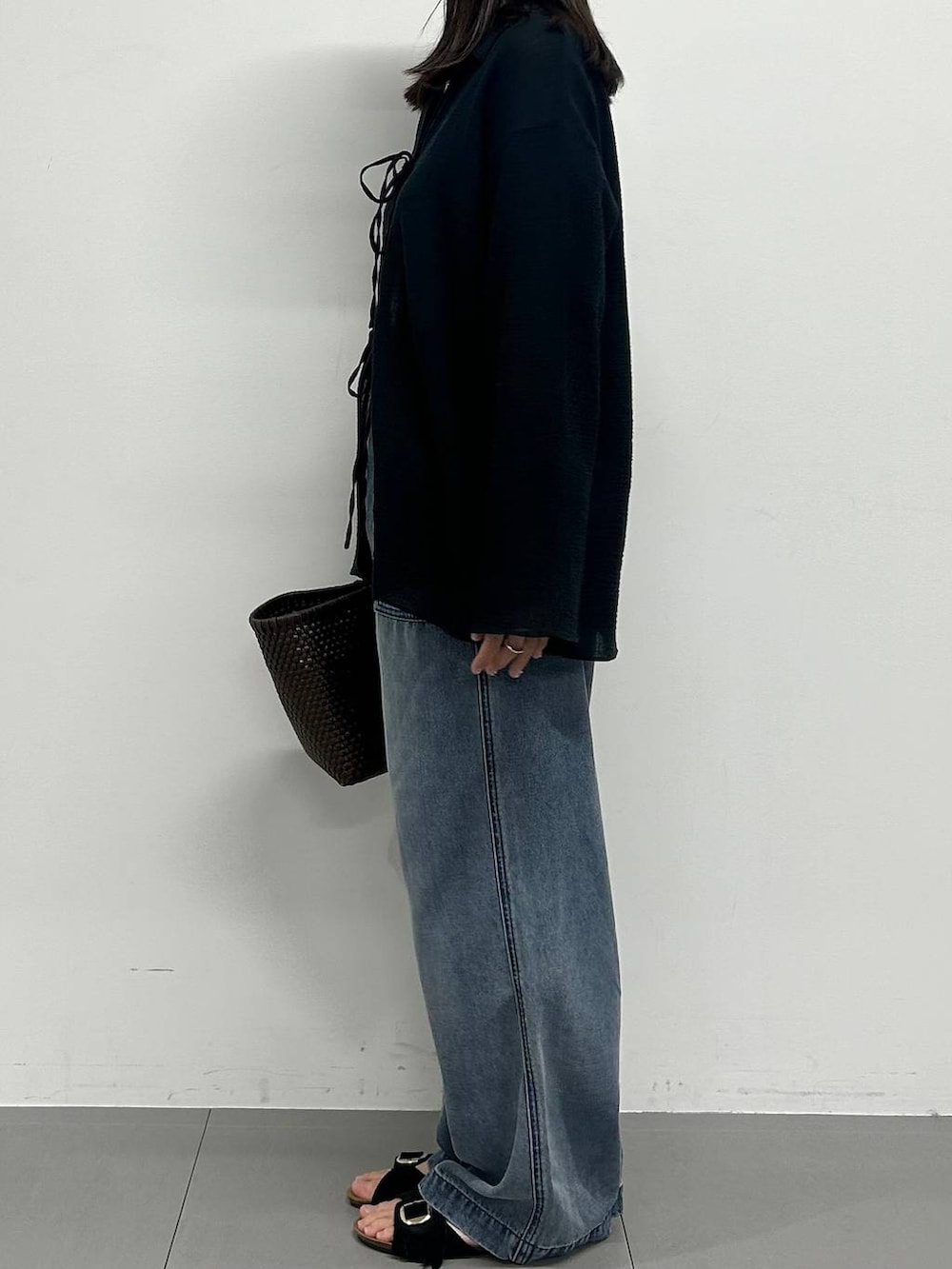 ブルー系のデニムパンツ、ブラック系のサンダルを着用したレディースの春コーディネートの2枚目の写真