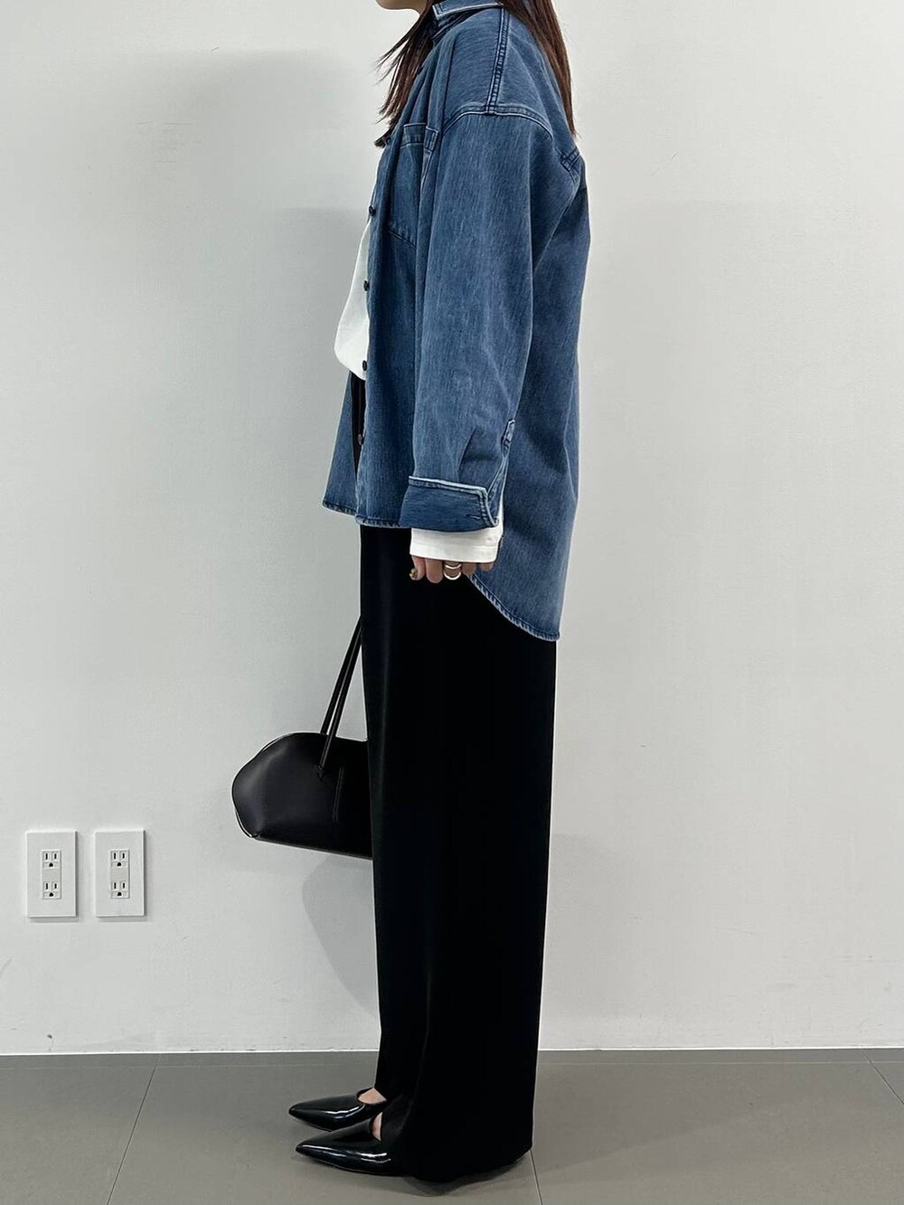 ブラウン系のトートバッグ、ブラック系のスラックスを着用したレディースの冬コーディネートの2枚目の写真