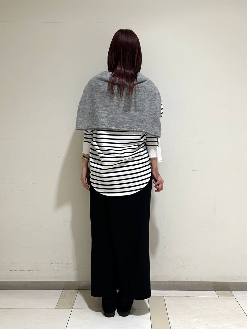 ブラック系のスカート、グレー系のニット/セーター、ホワイト系のTシャツ/カットソーを着用したレディースの冬コーディネートの3枚目の写真