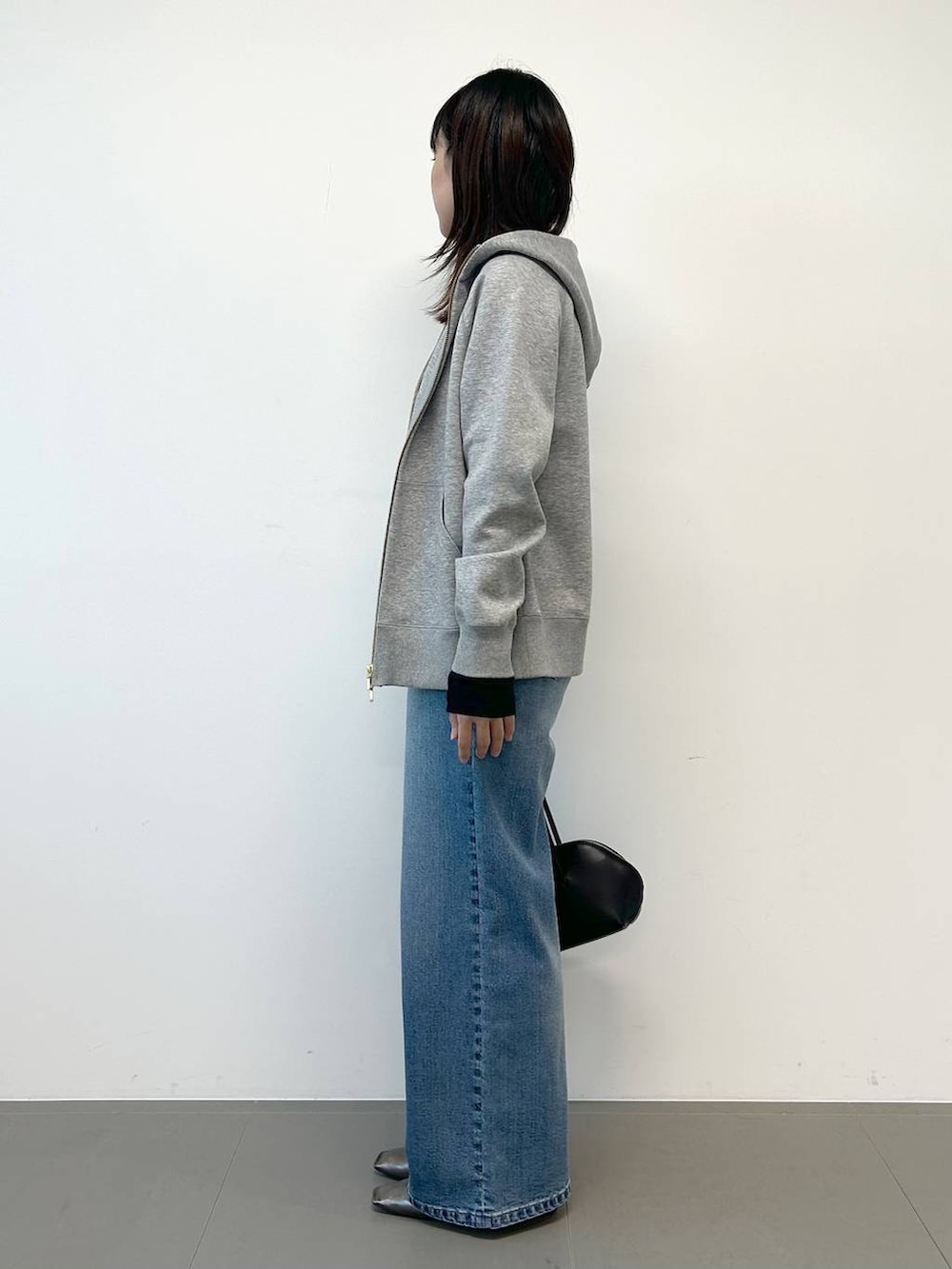 ブルー系のデニムパンツ、ブラック系のトートバッグ、シルバー系のパンプスを着用したレディースの秋コーディネートの2枚目の写真