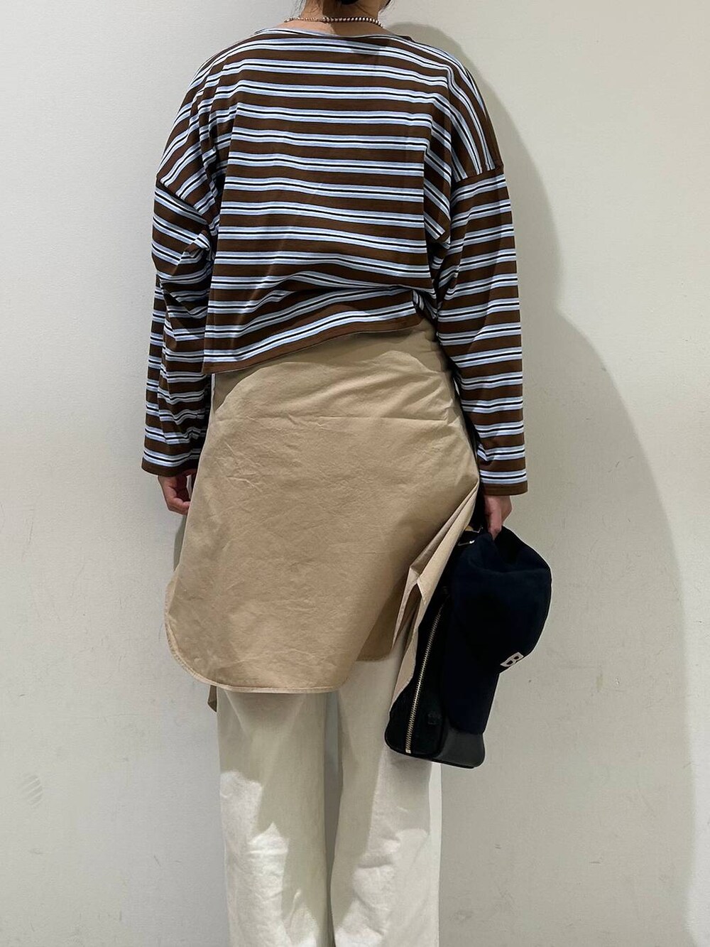 ホワイト系のデニムパンツ、ブラウン系のTシャツ/カットソー、ブラック系のショルダーバッグを着用したレディースの冬コーディネートの3枚目の写真