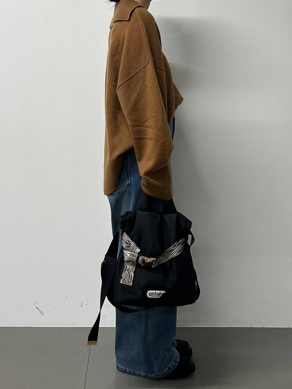 ブルー系のデニムパンツ、イエロー系のニット/セーター、その他のショルダーバッグを着用したレディースの秋コーディネートの2枚目の写真