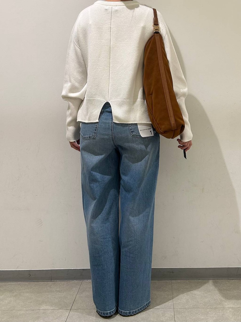 ブルー系のデニムパンツ、ホワイト系のニット/セーター、ブラック系のパンプスを着用したレディースの冬コーディネートの3枚目の写真