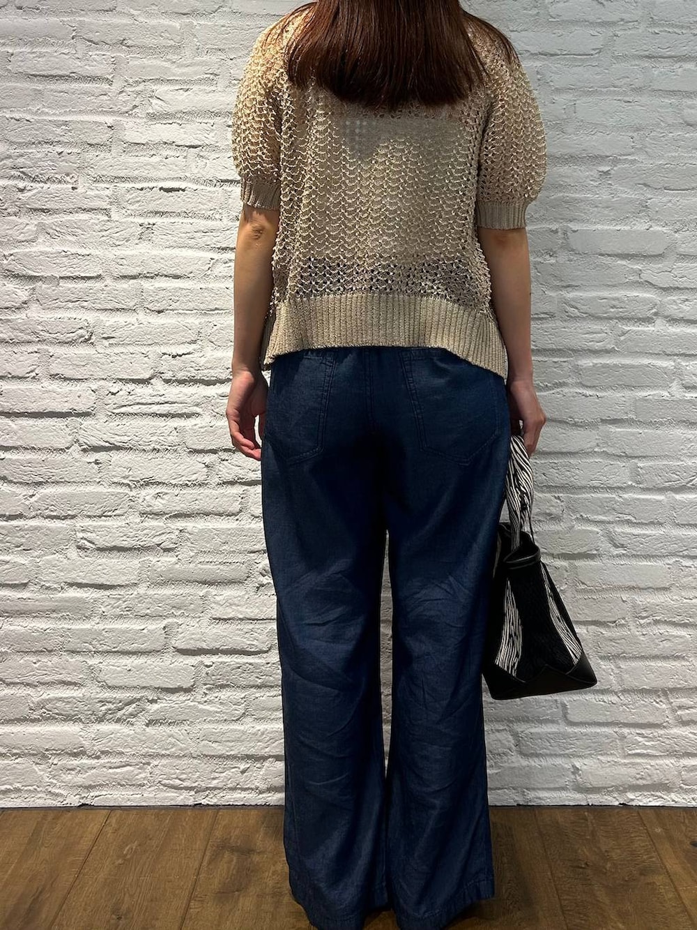 ブラック系のトートバッグ、ブラウン系のサンダル、ブルー系のデニムパンツを着用したレディースの夏コーディネートの3枚目の写真