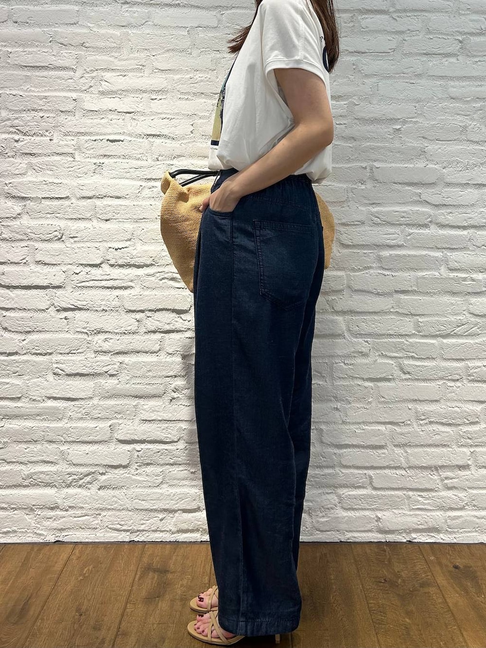ホワイト系のTシャツ/カットソー、ベージュ系のサンダル、ブルー系のデニムパンツを着用したレディースの夏コーディネートの2枚目の写真