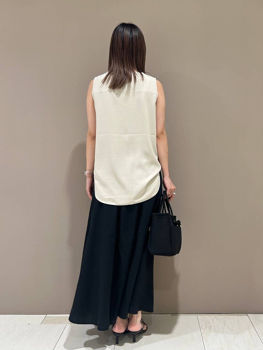 ブラック系のスリッポン、ブラック系のトートバッグ、ホワイト系のTシャツ/カットソーを着用したレディースの夏コーディネートの3枚目の写真