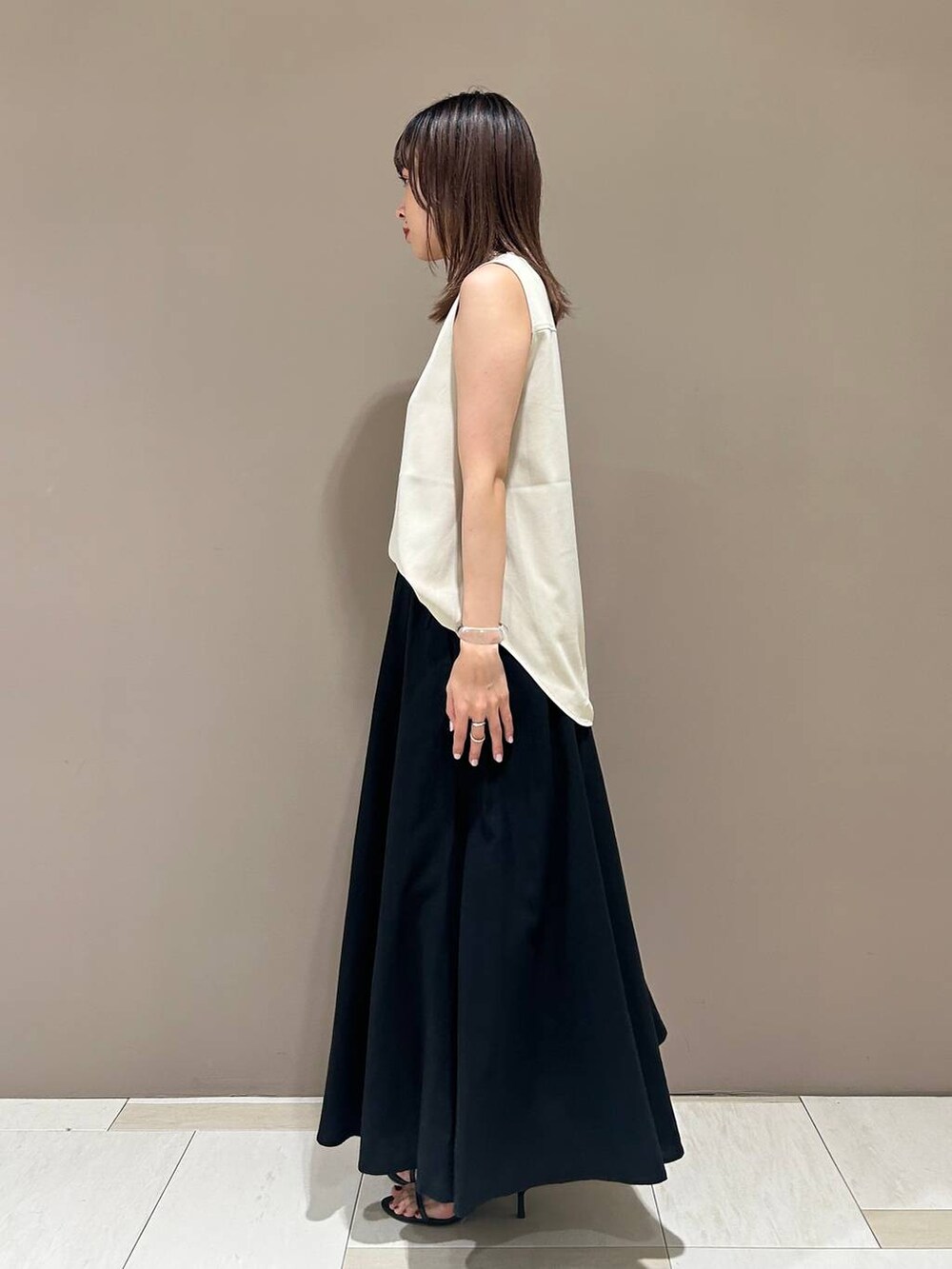 ブラック系のスリッポン、ブラック系のトートバッグ、ホワイト系のTシャツ/カットソーを着用したレディースの夏コーディネートの2枚目の写真