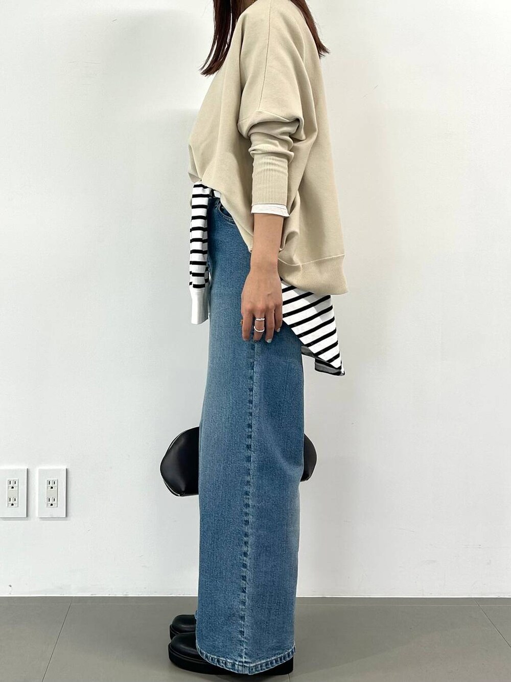 ブルー系のデニムパンツ、ブラウン系のトートバッグ、ホワイト系のTシャツ/カットソーを着用したレディースの冬コーディネートの2枚目の写真