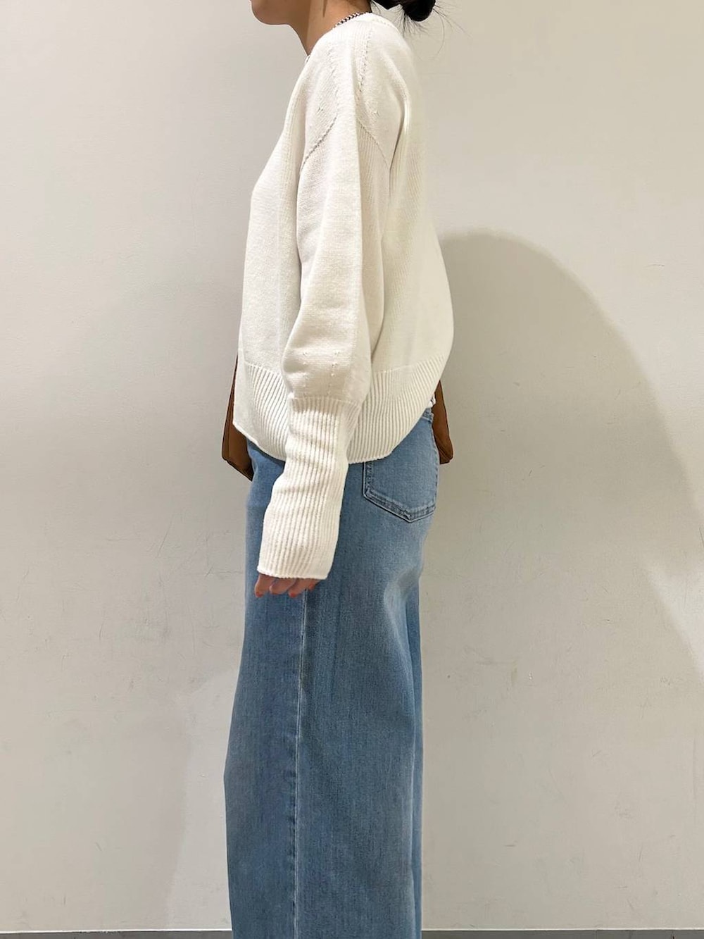 ブルー系のデニムパンツ、ホワイト系のニット/セーター、ブラック系のパンプスを着用したレディースの冬コーディネートの2枚目の写真