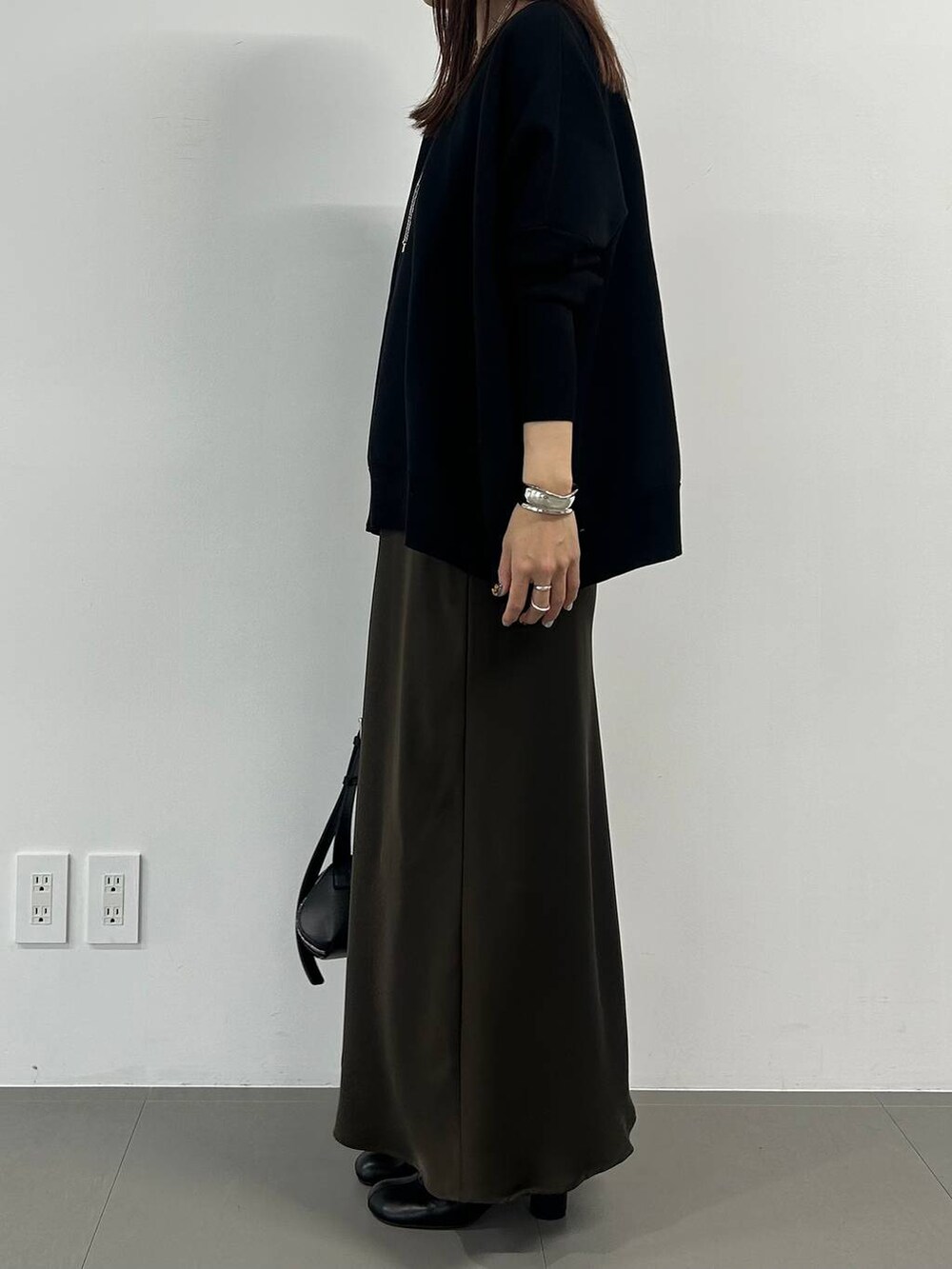 ブラック系のブーツ、ブラウン系のスカート、シルバー系のネックレスを着用したレディースの冬コーディネートの2枚目の写真