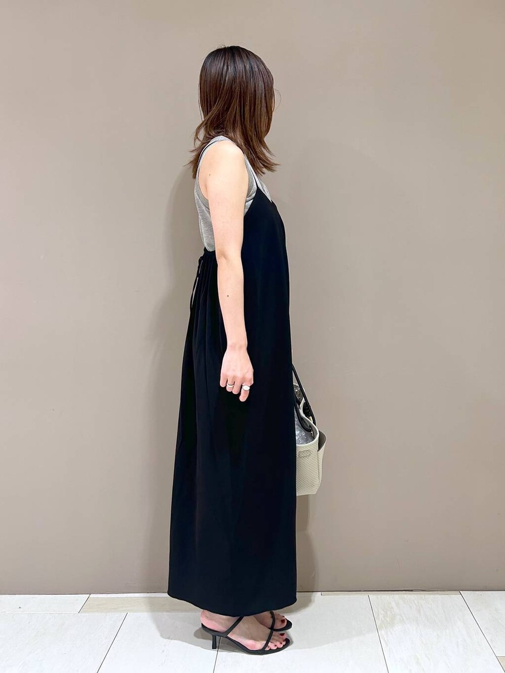 ブラック系のスリッポン、ベージュ系のトートバッグ、ベージュ系のニット/セーターを着用したレディースの夏コーディネートの2枚目の写真