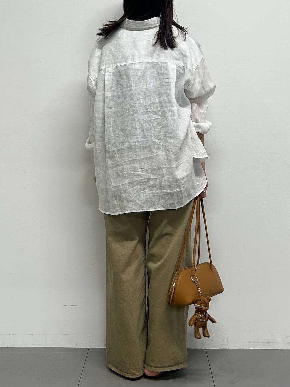 ブラウン系のハンドバッグ、ホワイト系のシャツ/ブラウス、イエロー系のキーホルダーを着用したレディースの春コーディネートの3枚目の写真