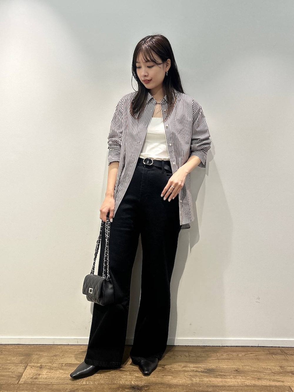 ブラック系のハンドバッグ、ベージュ系のシャツ/ブラウス、ブラック系のデニムパンツを着用したレディースの秋コーディネートの2枚目の写真