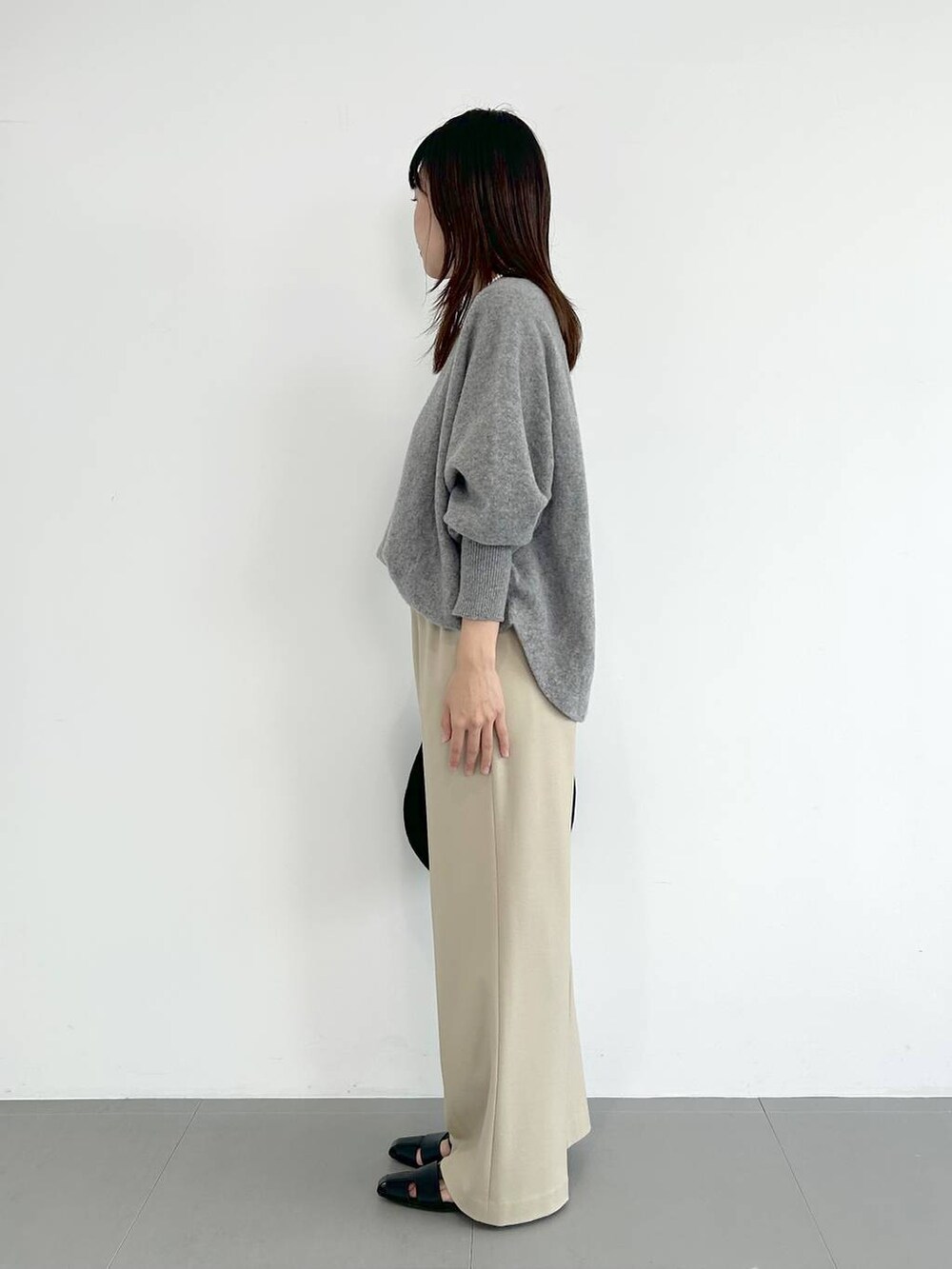 ブラック系のトートバッグ、ブラック系のパンプス、その他のネックレスを着用したレディースの秋コーディネートの2枚目の写真