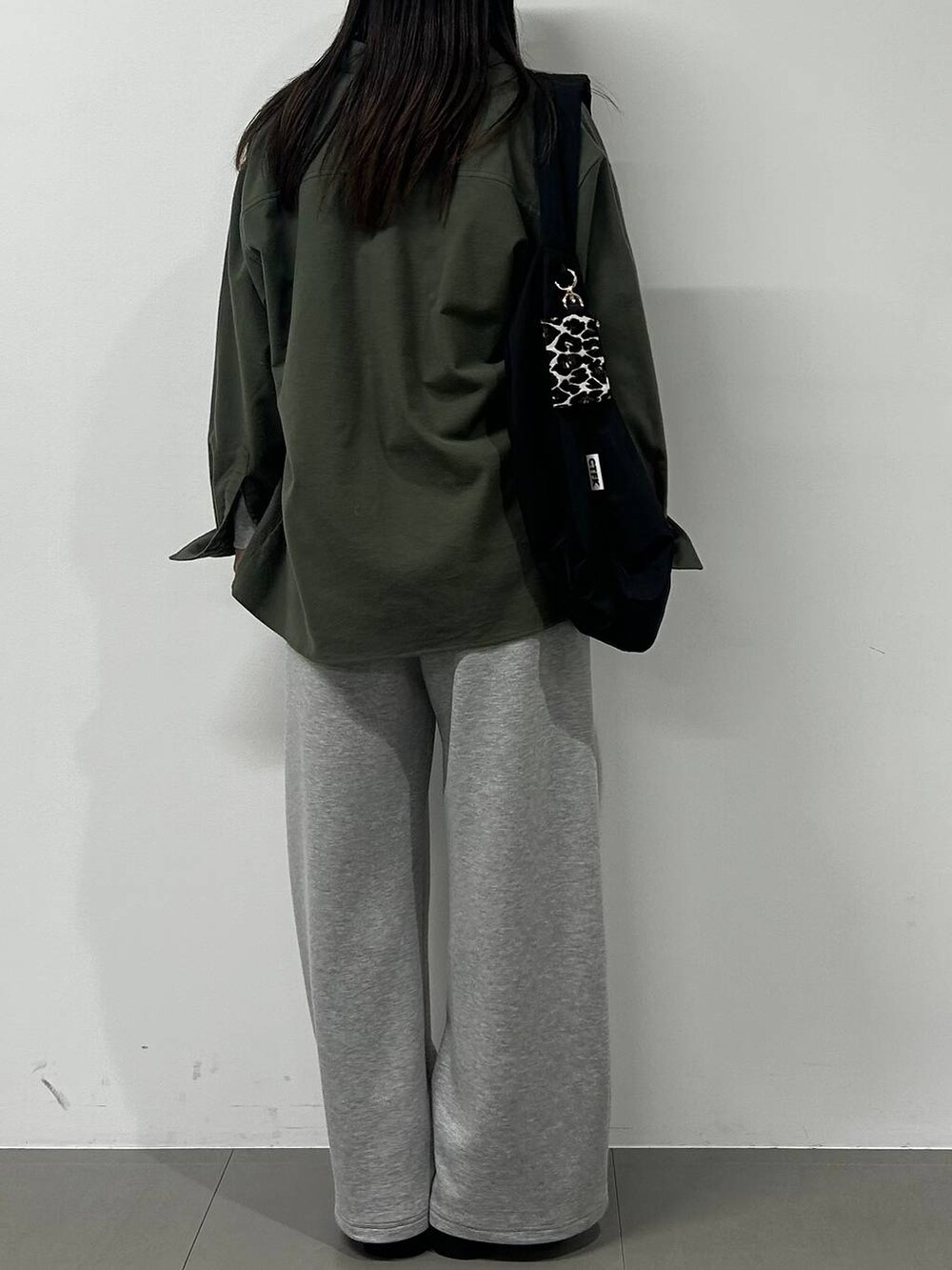 ブラック系のショルダーバッグ、ブラック系のスリッポン、グレー系のTシャツ/カットソーを着用したレディースの冬コーディネートの3枚目の写真