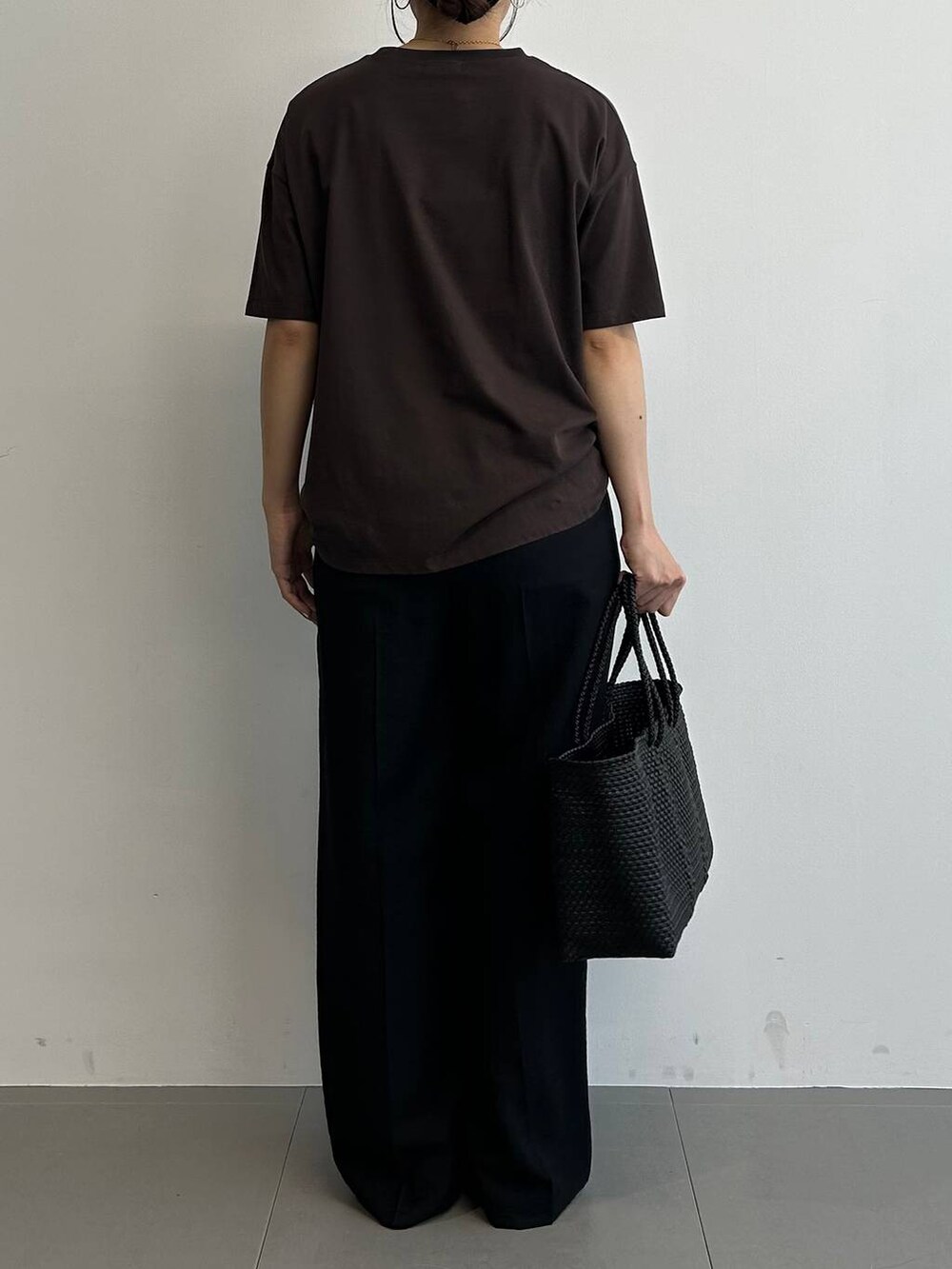 ブラック系のトートバッグ、ブラック系のサンダル、ブラウン系のTシャツ/カットソーを着用したレディースの夏コーディネートの3枚目の写真