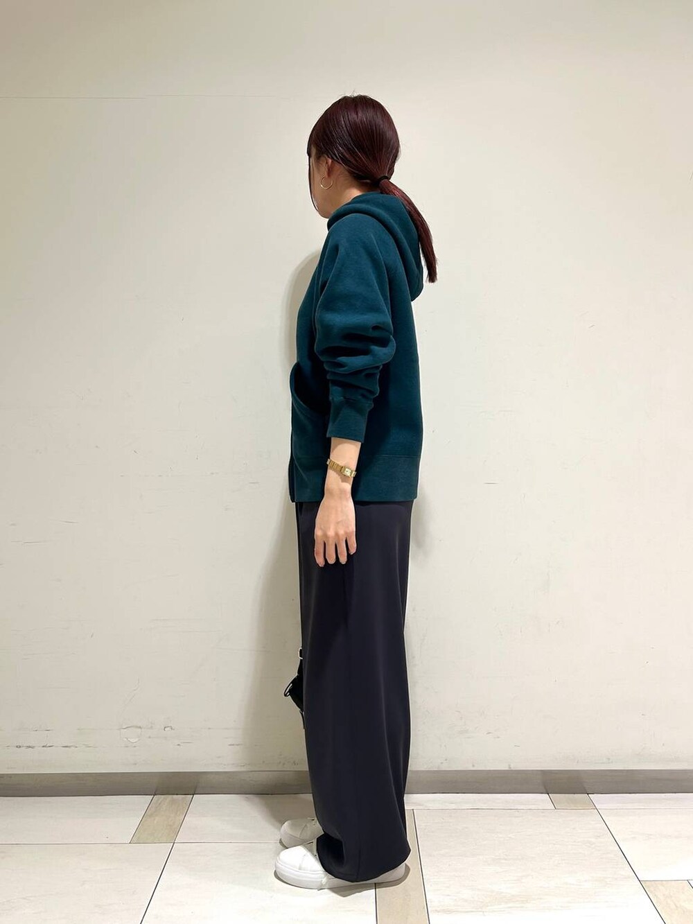 ブラック系のボディバッグ/ウエストポーチ、ホワイト系のスニーカー、グリーン系のパーカーを着用したレディースの冬コーディネートの2枚目の写真