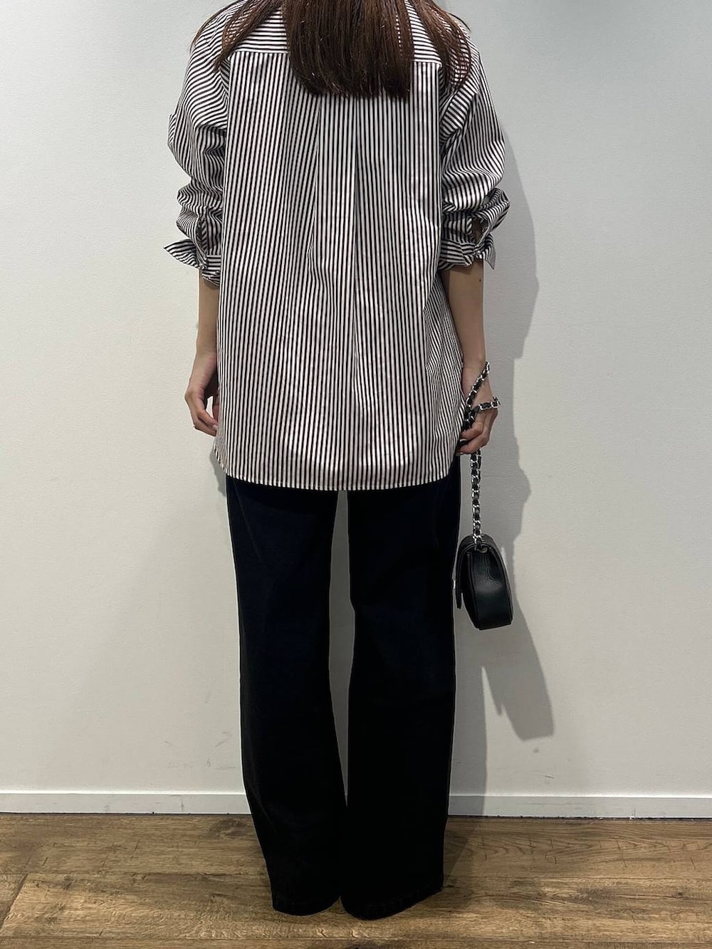 ブラック系のハンドバッグ、ベージュ系のシャツ/ブラウス、ブラック系のデニムパンツを着用したレディースの秋コーディネートの3枚目の写真