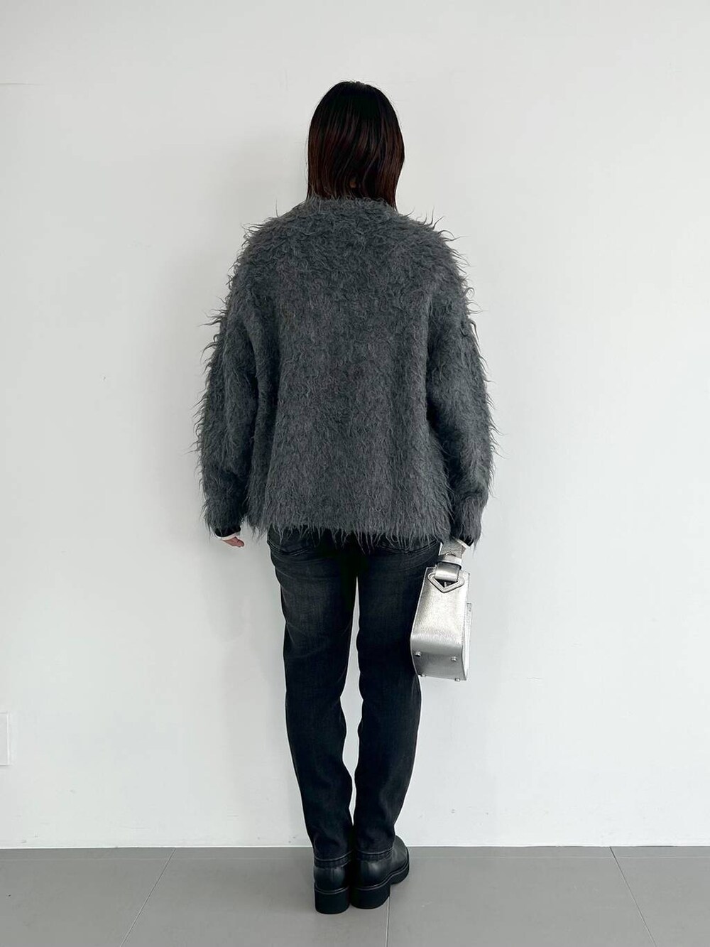 シルバー系のショルダーバッグ、ブラック系のデニムパンツ、ホワイト系のニット/セーターを着用したレディースの秋コーディネートの2枚目の写真