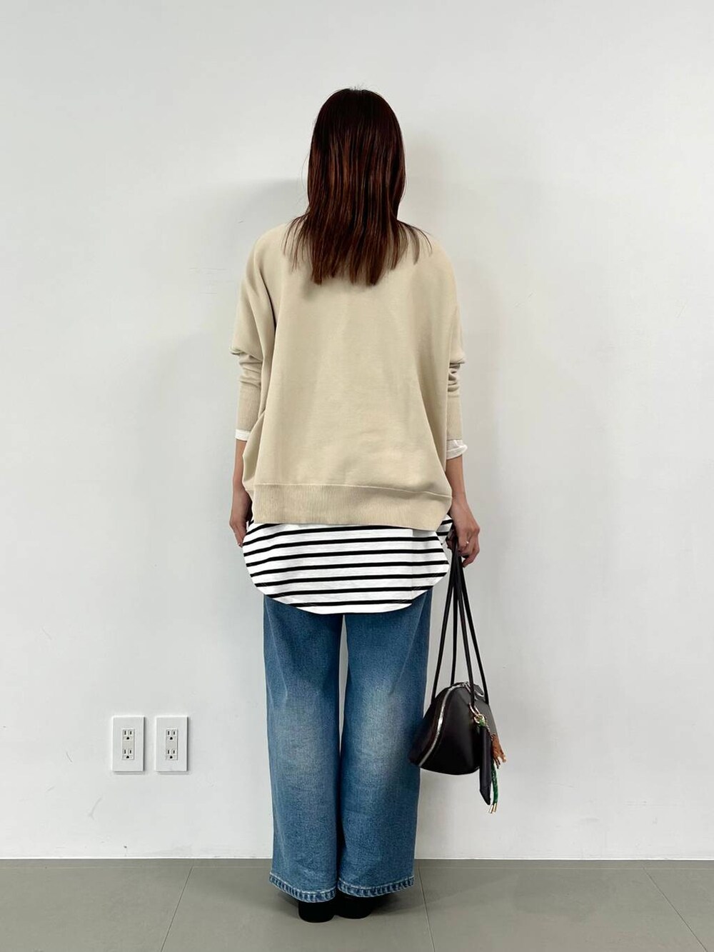 ブルー系のデニムパンツ、ブラウン系のトートバッグ、ホワイト系のTシャツ/カットソーを着用したレディースの冬コーディネートの3枚目の写真