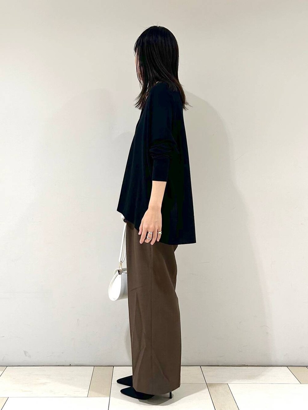 ブラウン系のスラックス、ブラック系のカーディガン/ボレロ、ホワイト系のショルダーバッグを着用したレディースの夏コーディネートの2枚目の写真