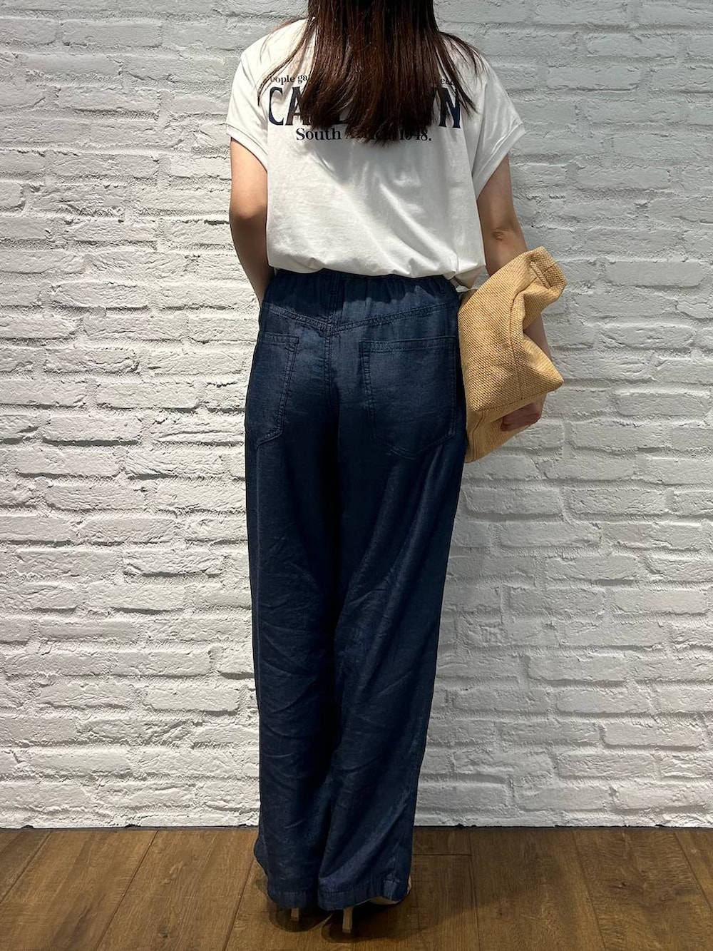 ホワイト系のTシャツ/カットソー、ベージュ系のサンダル、ブルー系のデニムパンツを着用したレディースの夏コーディネートの3枚目の写真