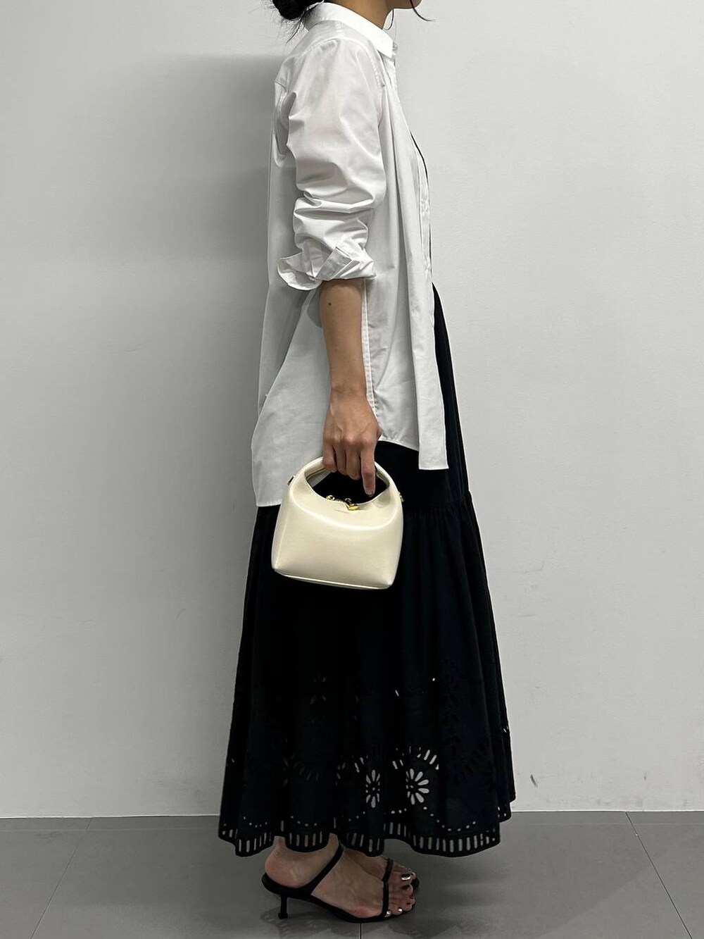 ブラック系のサンダル、ホワイト系のハンドバッグ、ブラック系のスカートを着用したレディースの夏コーディネートの2枚目の写真