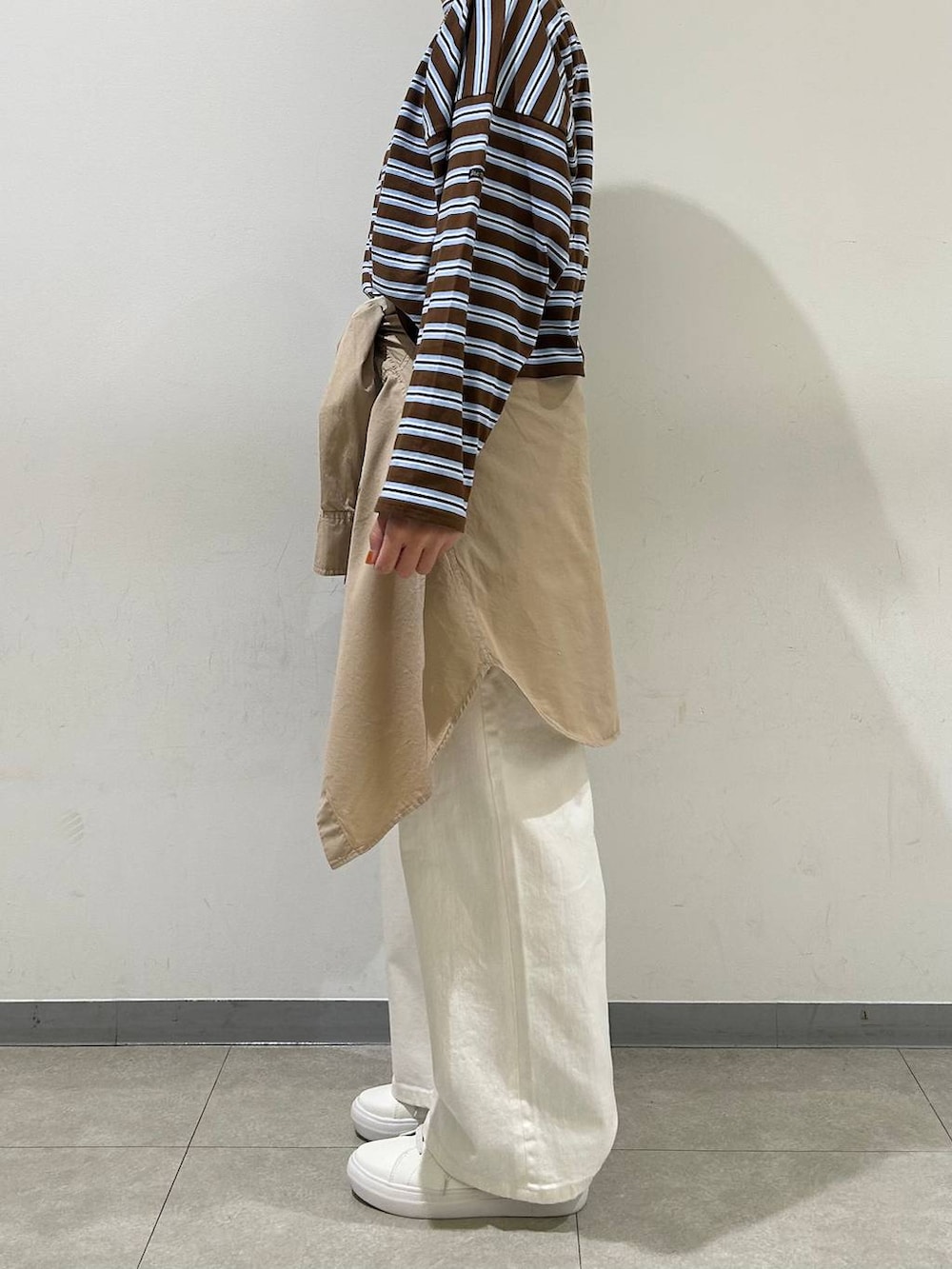 ホワイト系のデニムパンツ、ブラウン系のTシャツ/カットソー、ブラック系のショルダーバッグを着用したレディースの冬コーディネートの2枚目の写真