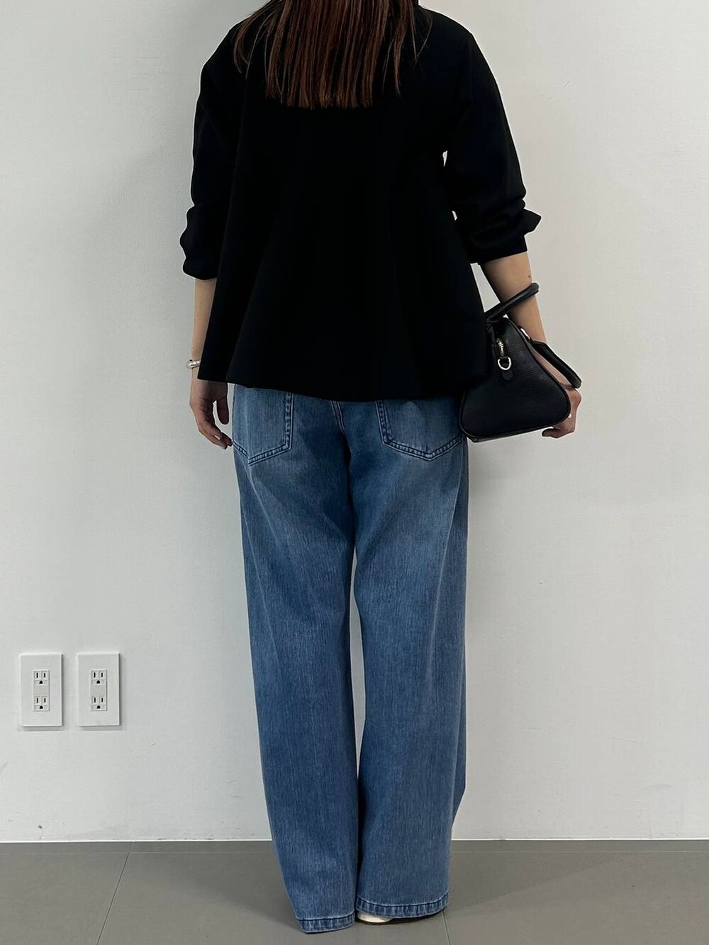 ブルー系のデニムパンツ、ホワイト系のパンプス、ブラック系のニット/セーターを着用したレディースの冬コーディネートの3枚目の写真