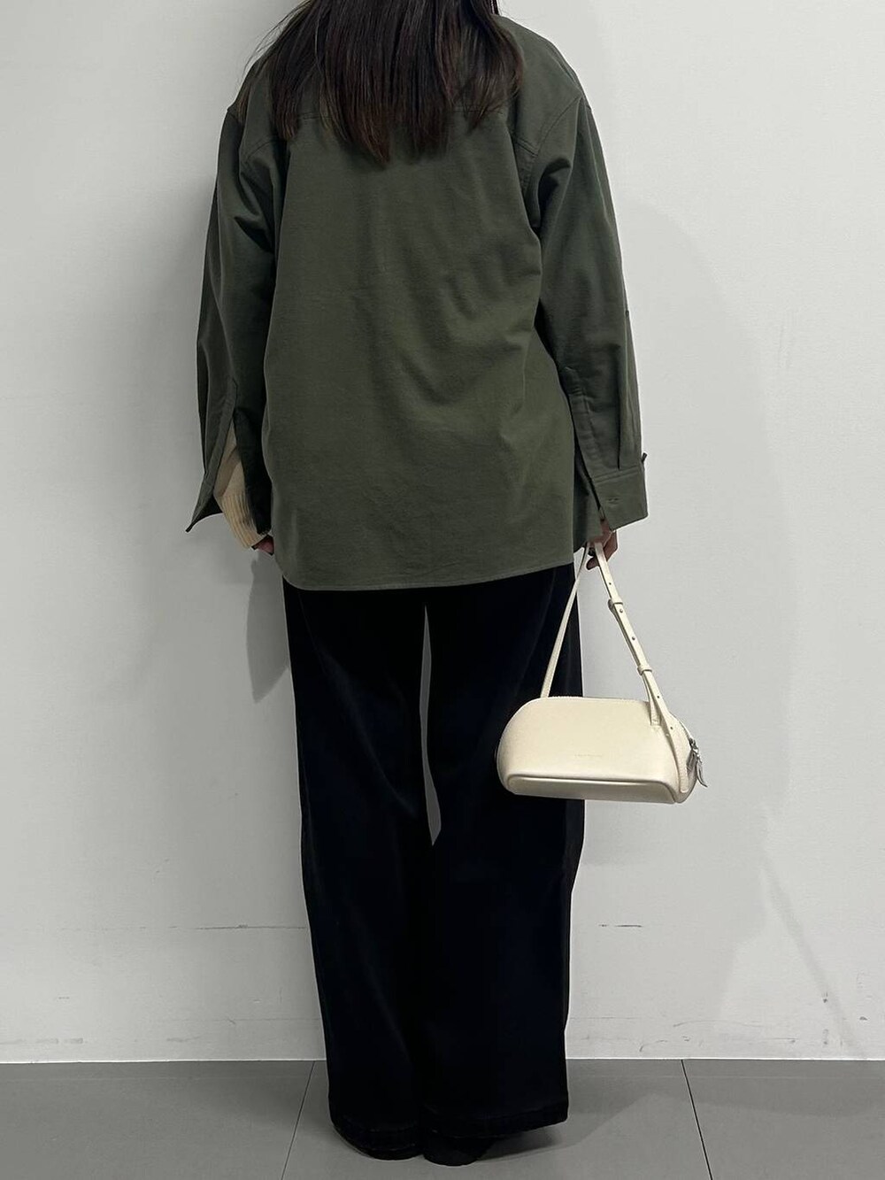 ホワイト系のショルダーバッグ、ブラック系のデニムパンツ、ブラック系のブーツを着用したレディースの秋コーディネートの3枚目の写真