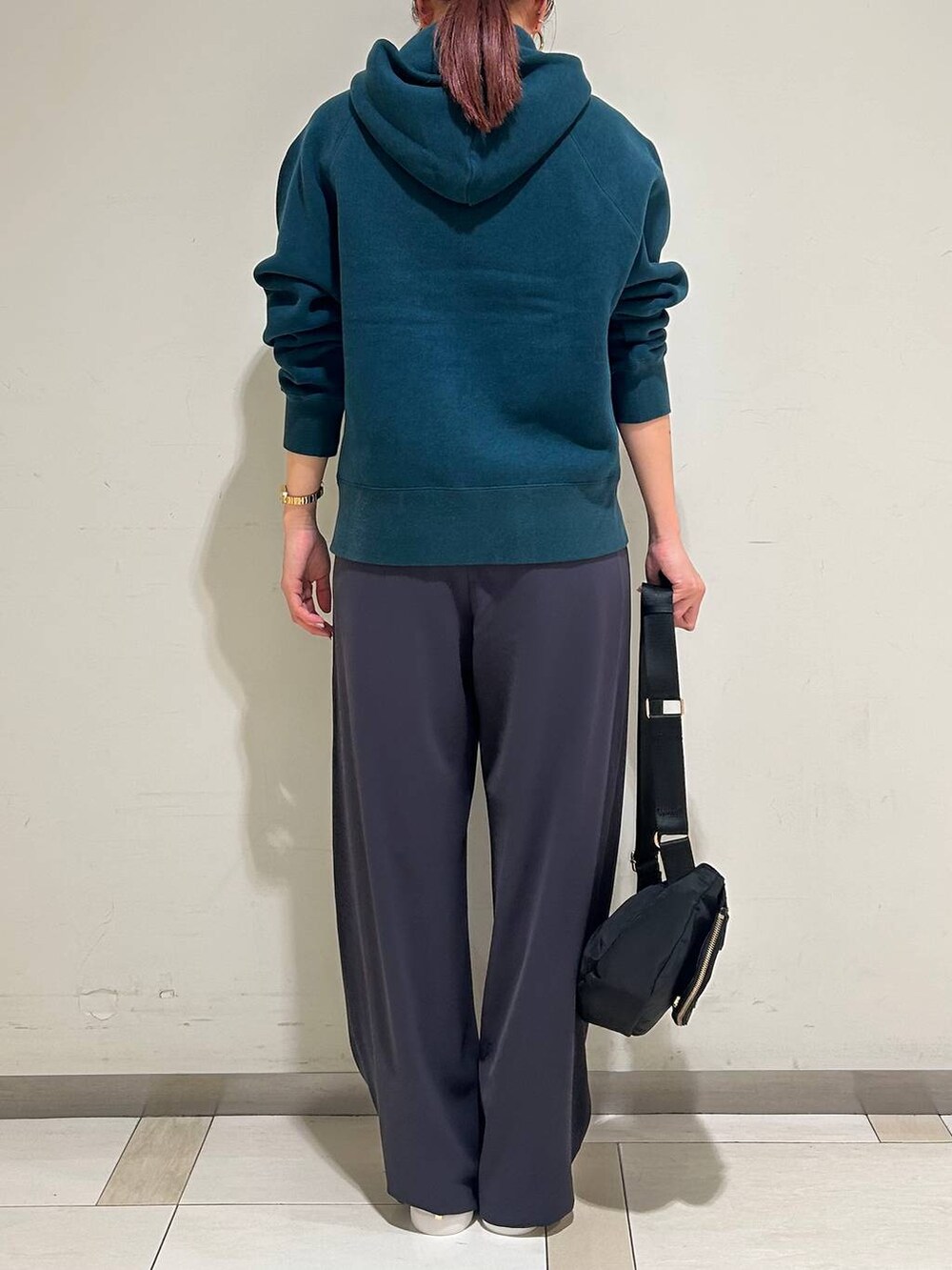 ブラック系のボディバッグ/ウエストポーチ、ホワイト系のスニーカー、グリーン系のパーカーを着用したレディースの冬コーディネートの3枚目の写真