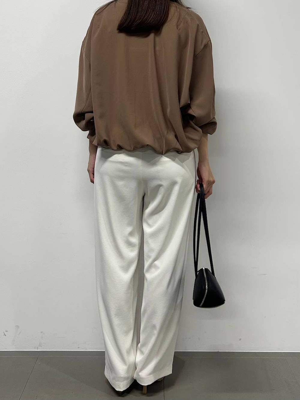 ホワイト系のスラックス、イエロー系のブルゾン、ブラック系のハンドバッグを着用したレディースの春コーディネートの4枚目の写真