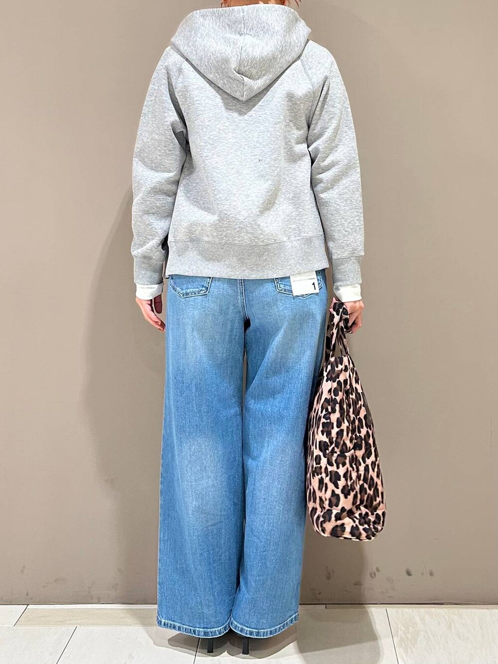 ブラック系のスリッポン、ブルー系のデニムパンツ、グレー系のパーカーを着用したレディースの春コーディネートの3枚目の写真