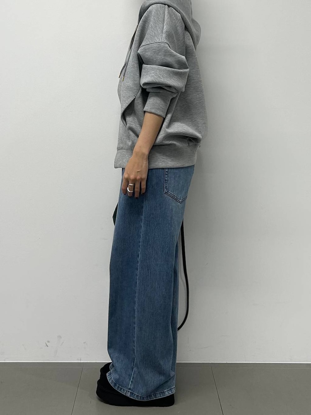 ブルー系のデニムパンツ、ブラック系のショルダーバッグ、グレー系のパーカーを着用したレディースの秋コーディネートの2枚目の写真