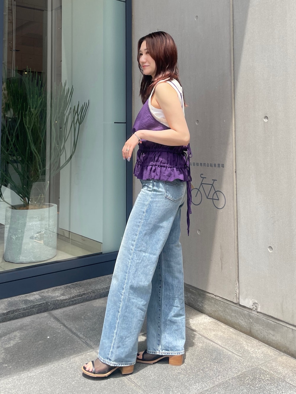 パープル系のタンクトップ、ブルー系のデニムパンツ、ブラック系のサンダルを着用したレディースの夏コーディネートの3枚目の写真