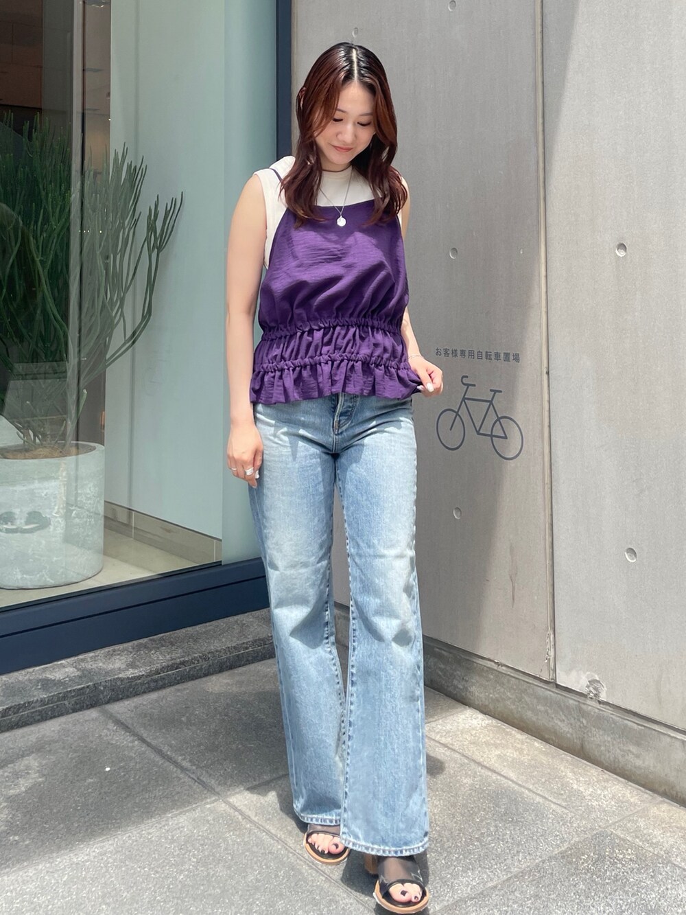 パープル系のタンクトップ、ブルー系のデニムパンツ、ブラック系のサンダルを着用したレディースの夏コーディネートの2枚目の写真