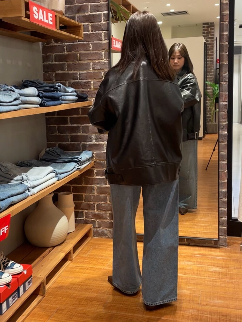 ブラック系のブルゾン、ブルー系のシャツ/ブラウス、ブルー系のデニムパンツを着用したレディースの冬コーディネートの3枚目の写真