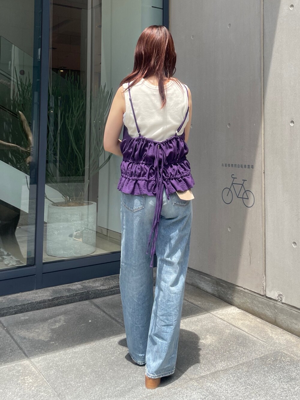 パープル系のタンクトップ、ブルー系のデニムパンツ、ブラック系のサンダルを着用したレディースの夏コーディネートの4枚目の写真